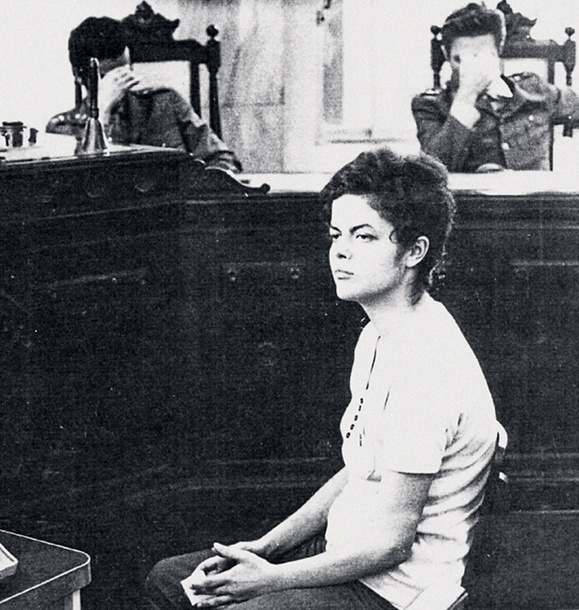 Dilma em interrogat&oacute;rio; ao fundo, oficiais cobrem o rosto