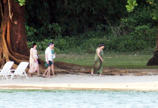 Dilma caminhando na praia ao lado da família.