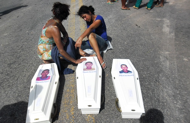 Os caix&otilde;es foram colocados no meio da rodovia. M&atilde;e e prima de um dos jovens assassinados, aos prantos, pr&oacute;ximas aos caix&otilde;es com os restos mortais das v&iacute;timas