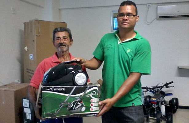 Um dos ganhadores recebendo um pr&ecirc;mio das m&atilde;os de um funcion&aacute;rio da empresa