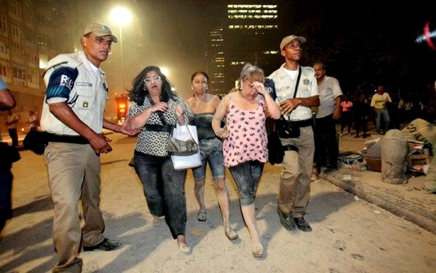 Amparadas por guardas municipais e policiais, mulheres cobertas de poeira caminham pela Avenida Treze de Maio, local do acidente